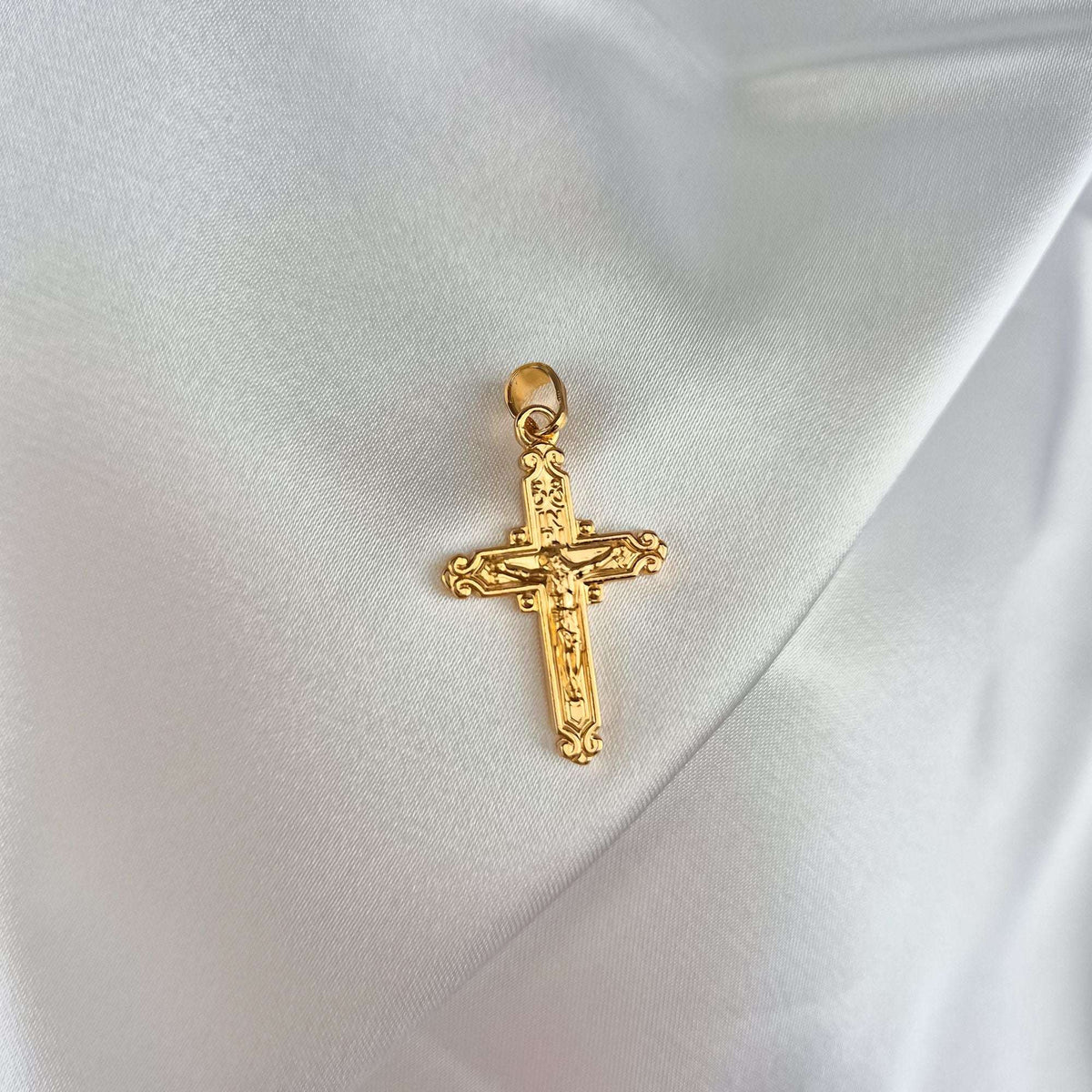 Kullatud katoliku ristiripats Kristuse kuju ja INRI kirjaga valgel atlassiidil